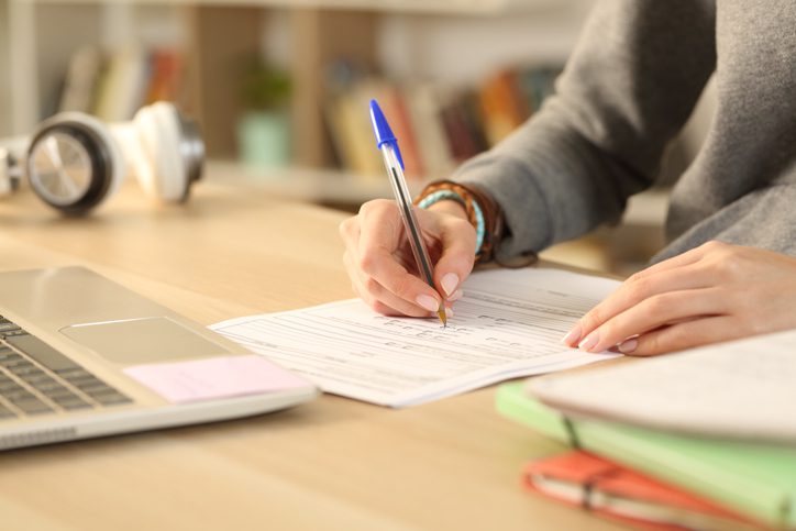 Student hands filling out form document at home